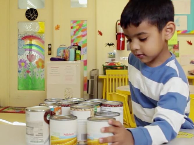 A child in a classroom with canned goods