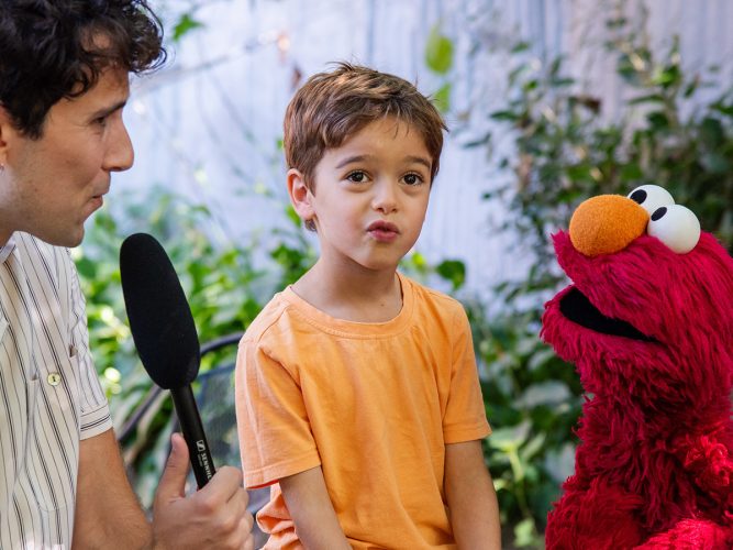 Julian from Recess Therapy and Elmo interview a child.