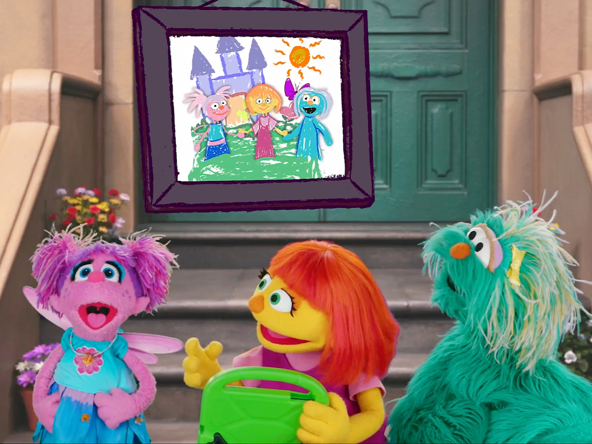 Abby, Julia, and Rosita pose with a drawing of themselves