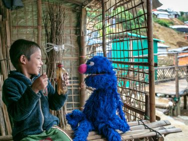 Grover sits with a child