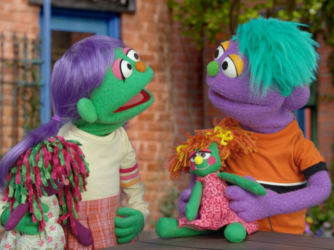 Two muppet children playing with dolls.