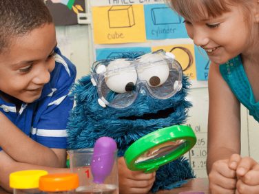 Cookie Monster and kids with a magnifying glass.