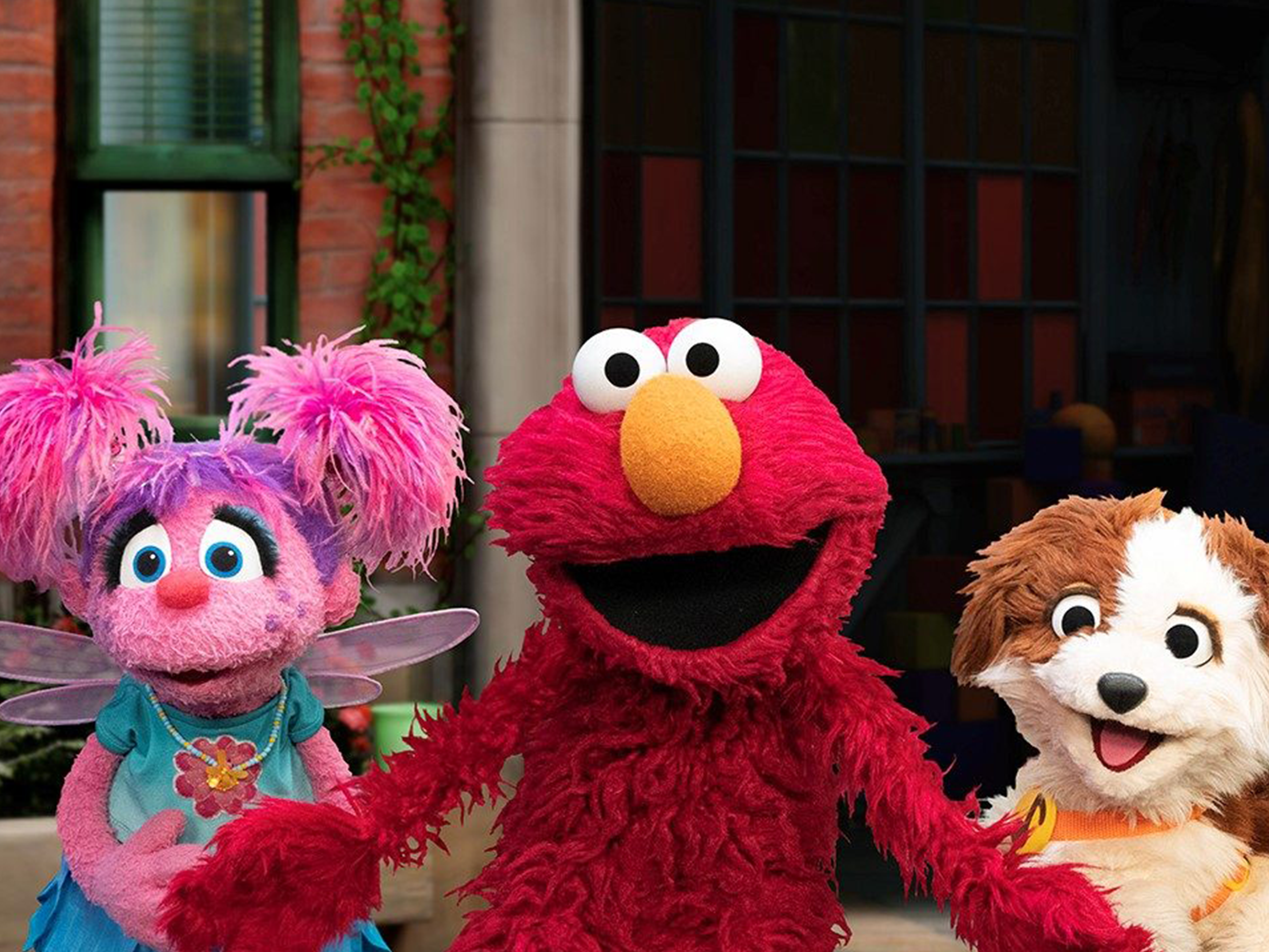 Elmo, Abby, and Tango smile and pose together.