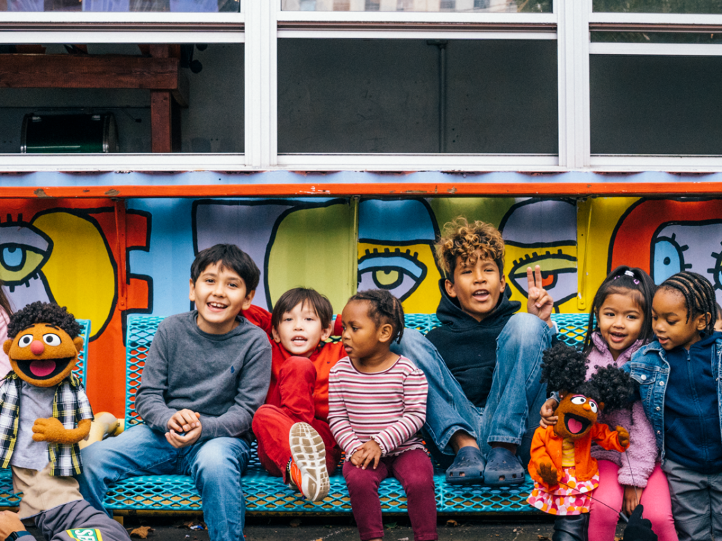 Sesame Street Muppets and kids on a bench.